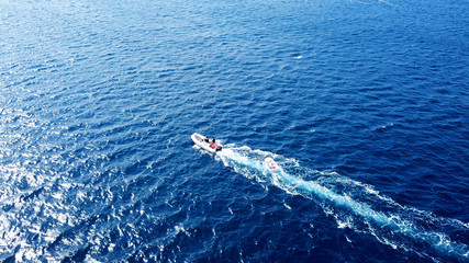 Aerial bird's eye drone photo of small sailboat cruising in deep blue sea