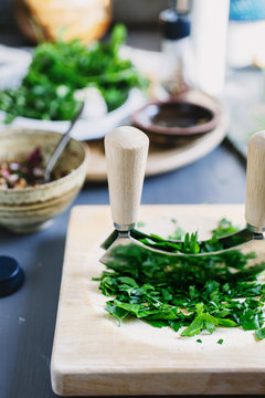 Using a herb cutter to chop parsley on a table.