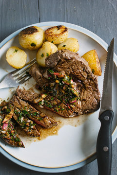 Steak on a plate with chimichurri sauce.