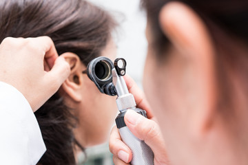 Doctor examined the patient's ear with Otoscope. Patient seem to have problems with hearing. - obrazy, fototapety, plakaty