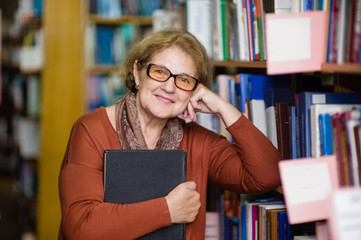 Smiling elderly woman with book in library