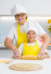 Mother teaches her son to roll out the dough