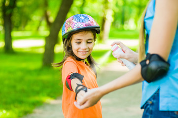 Mother spraying insect repellents on skin girl