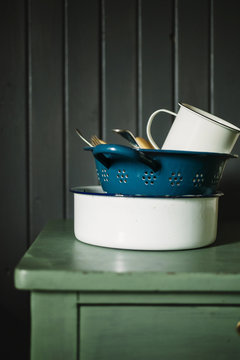 Vintage enamel kitchenware on green table against a grey background.