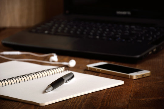 a desk with a notebook laptop pencil coffee phone and headphones writer's tabel 