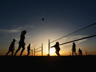 Fototapeta na wymiar People playing beach volleyball at sunset
