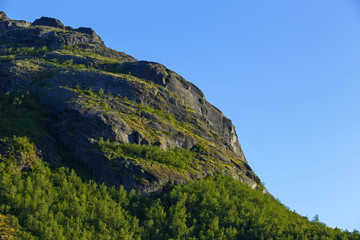 The mountain slope illuminated by the sun at sunset.