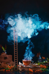 Cup of tea with dense steam forming a cloud. Wooden ladder rising to a cloud. Autumn still life on...
