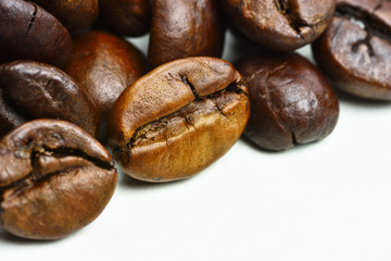 Close-up photo of grains of roasted black coffee on a white background
