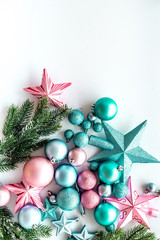 Christmas decoration pattern. Pink and blue stars and balls near pine branches on white background top view copyspace