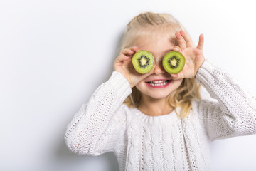 Cute girl 4-5 year old posing in studio with fruit kiwi
