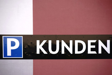 Obraz premium Kundenparkplatz / Ein Parkplatzschild für Kunden eines Wohn- und Geschäftsgebäudes vor einer zweifarbigen modernen Fassade.