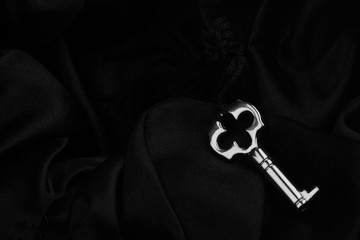 small silver key on dark silk background