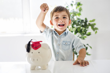 childhood, money, investment and happy people concept - smiling little boy with piggy bank and...