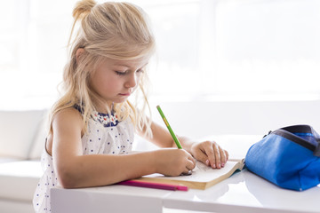 little girl drawing in the kitchen table