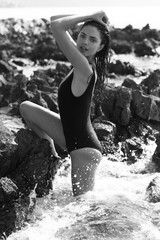 Beautiful girl is posing on the rocks and stones at the seaside.