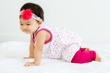 Portrait of adorable baby crawling on a white floor  with head band