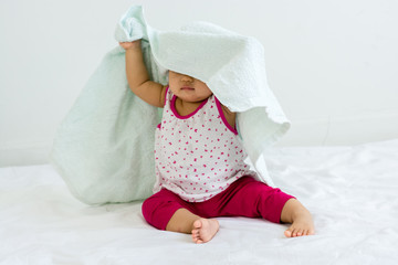 Portrait of adorable baby sitting with towel, indoors
