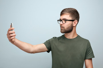 Young man taking selfie against color background