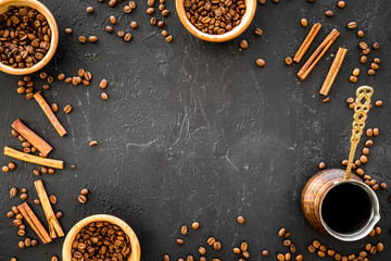 Ingredients for coffee. Roasted coffee beans and cinnamon on black background top view copyspace