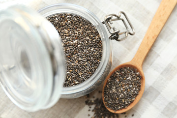 Chia seeds in jar and spoon on table