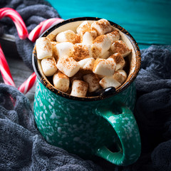Hot chocolate with marshmallows on green background. Christmas winter still life with red candy canes in heart shape