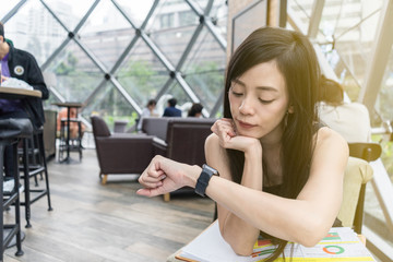 Business women rests her chin on her hand while watching her smartwatch