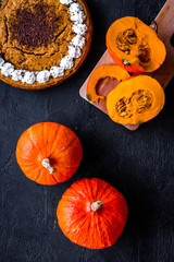 Make pumpkin pie. Whole cake near pumpkins on black background top view