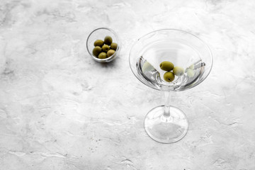 Martini cocktail in glass with olives at the bottom on grey stone background top view copyspace