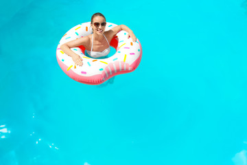 Young woman with inflatable donut in swimming pool