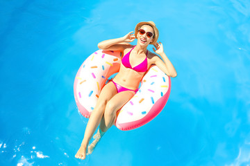Young woman relaxing on inflatable donut in swimming pool