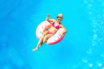 Young woman relaxing on inflatable donut in swimming pool
