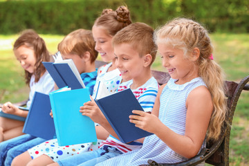 Cute little children reading books in park