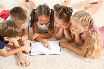 Cute little children reading book indoors