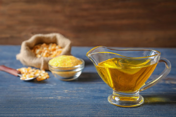 Glass gravy boat with corn oil on wooden background