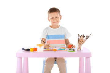 Talented boy painting while sitting at table against white background