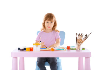 Talented girl painting while sitting at table against white background