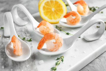 Spoons with delicious shrimps and lemon on board