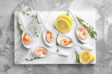 Spoons with delicious shrimps and lemon on board