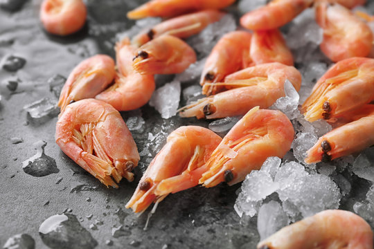 Frozen shrimps with ice on grey background