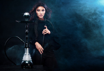 Young, beautiful woman in the night club or bar smoke a hookah. The pleasure of smoking. Sexy smoke.