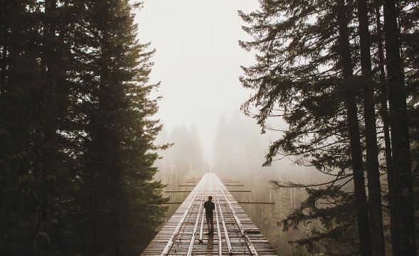 man standing on that PNW bridge on a foggy day