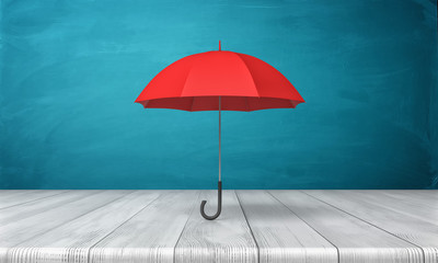 3d rendering of a single red classic umbrella with an open canopy standing above a wooden desk on blue background.
