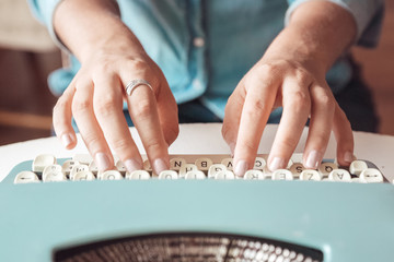Close up of woman hands writing with a vintage typewriter