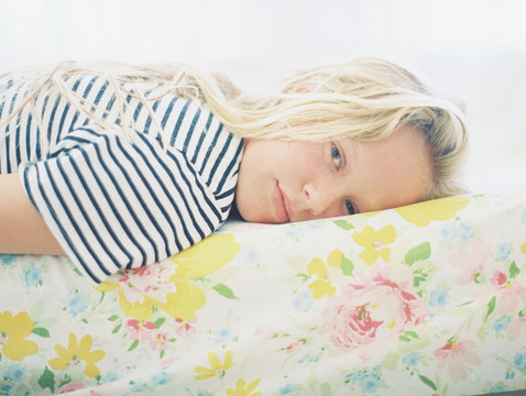 blonde girl tween in striped shirt on vintage floral sheet portrait