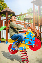 happy little girl riding motorcycle on playground alone in sunny weather