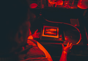 Man works on film black and white platinum print in laboratory.