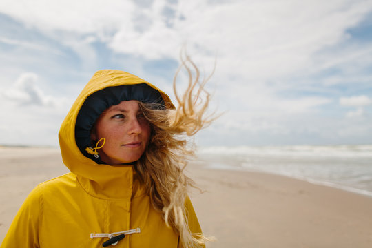 Woman on a windy beach wearing a yellow raincoat