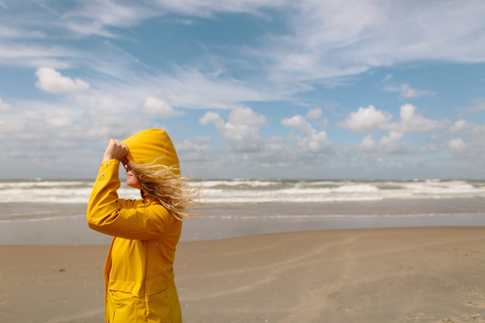 Woman on a windy beach wearing a yellow raincoat