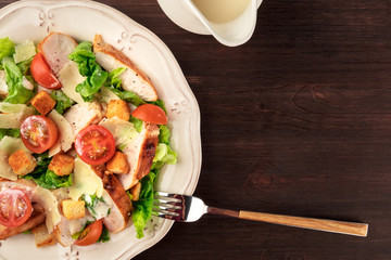 Chicken Caesar salad on dark rustic background with copyspace